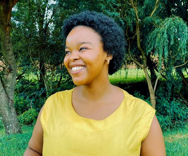 Person smiling peacefully outdoors in nature.